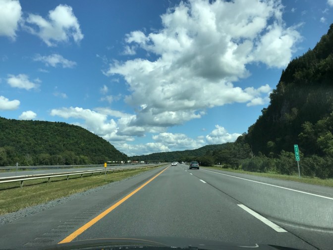 View of road through mountains beneath a blue sky.