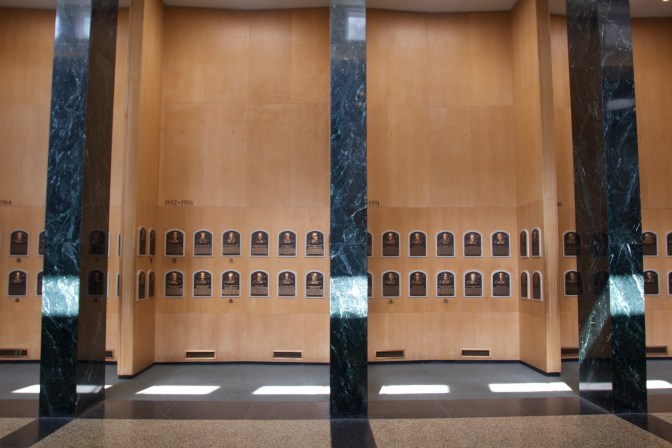Plaques on wooden walls with marble pillars in front of them.