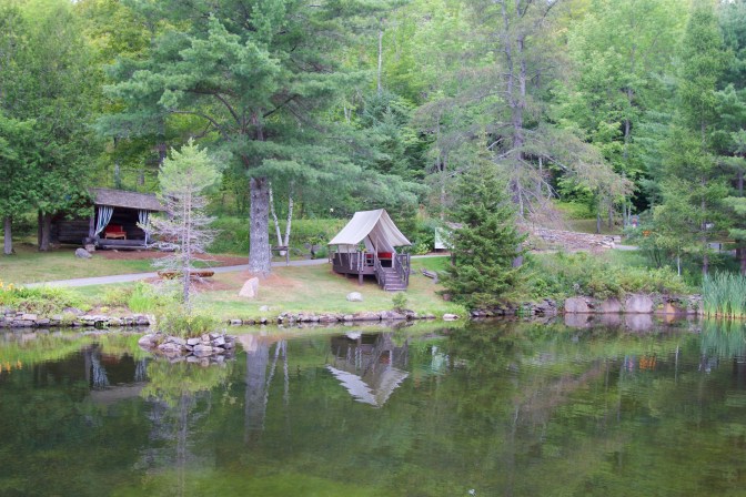 Tent and a lean-to beside a small pond.