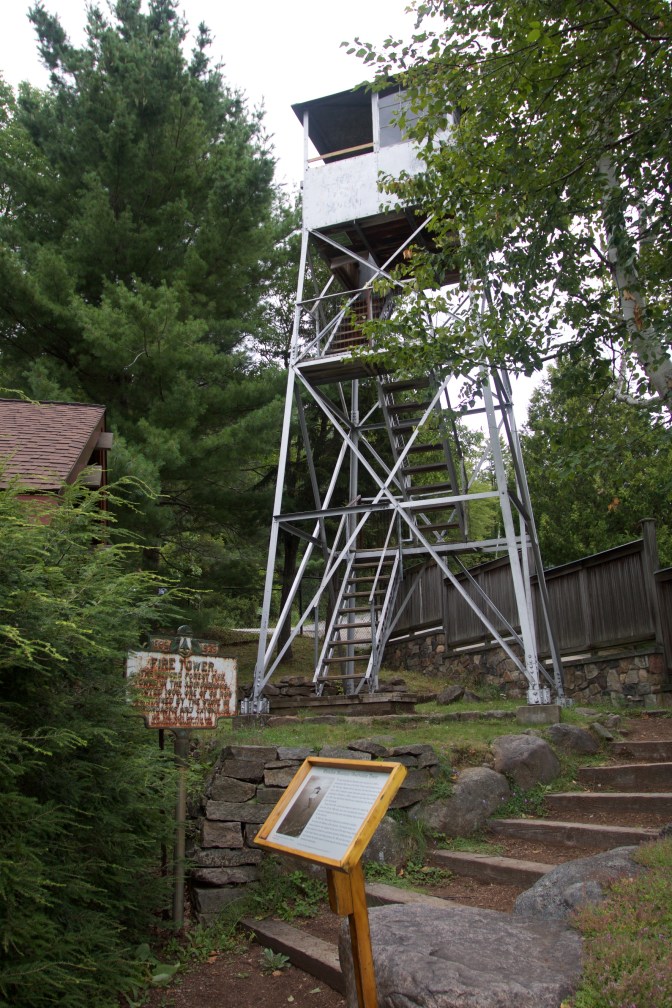 Fire Tower, in steel, with numerous signs in front of it.