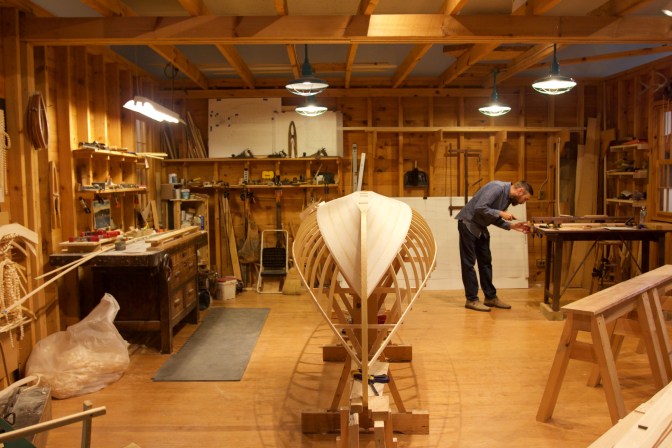 Boatbuilding workshop with worker in background.