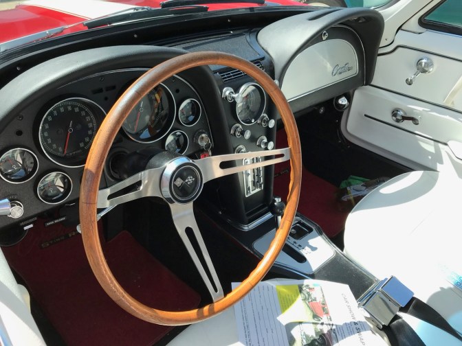 Interior of Corvette with black dashboard and white seats.