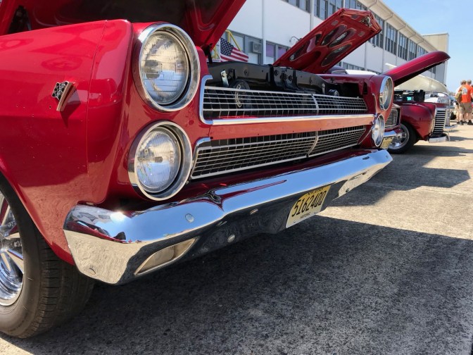 Noses of classic cars, including a red Pontiac GTO in the foreground.
