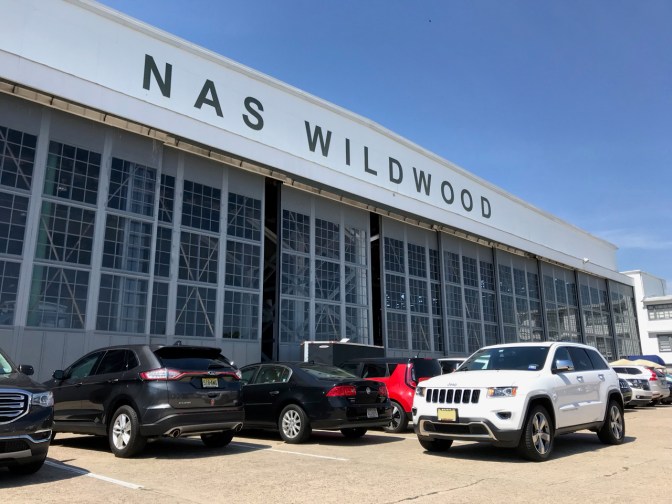 White Jeep Grand Cherokee parked in front of NAS Wildwood hangar.