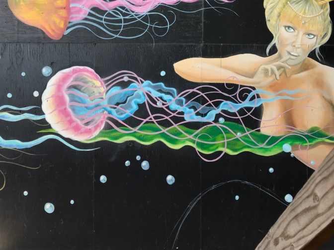 Mural of jellyfish swimming past mermaid.