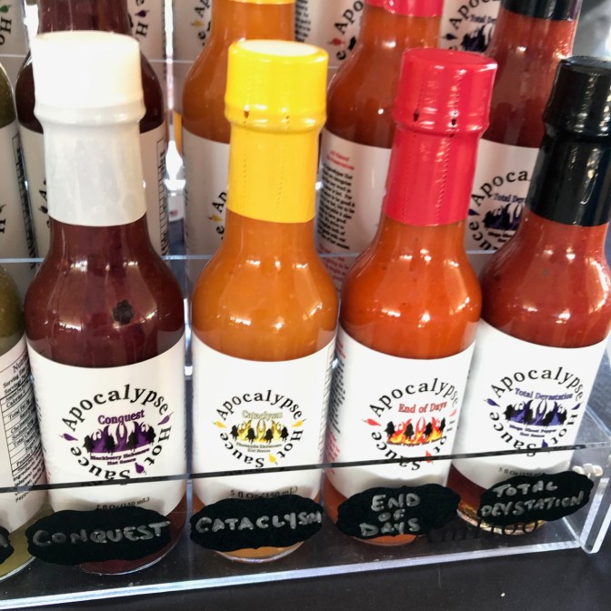 Hot sauce bottles, with signs that say CONQUEST, CATACLYSM, END OF DAYS, and TOTAL DEVASTATION.