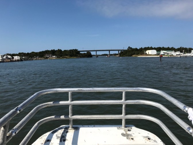 Bow of ship, with bridge in background across harbor.