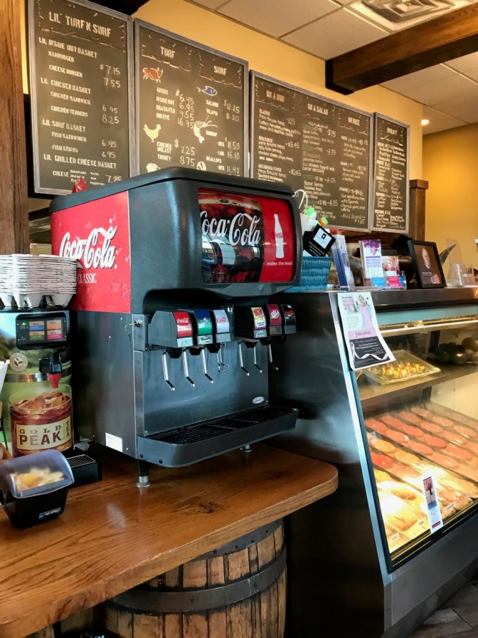 Counter, with chalkboard menu hanging behind counter, in restaurant.