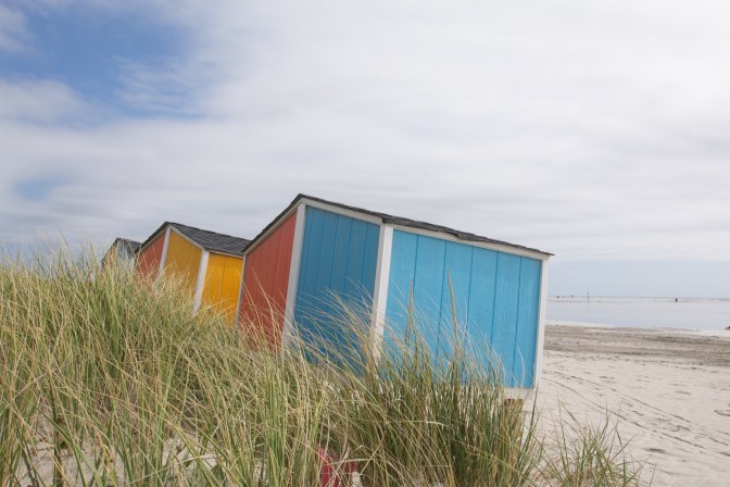 Blue, orange, and red storage huts on beach.