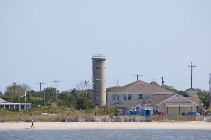 WWII Lookout tower, with buildings in foreground, and then the ocean.