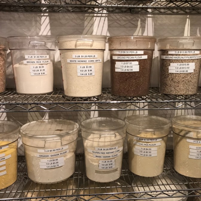Plastic buckets of different flours and ground nuts.