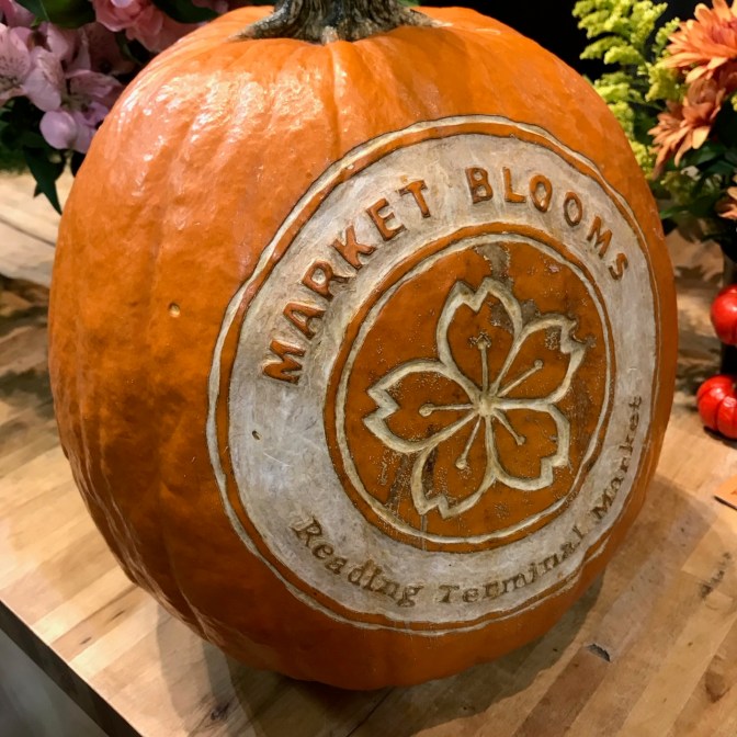 Pumpkin with MARKET BLOOMS READING TERMINAL MARKET carved into exterior.