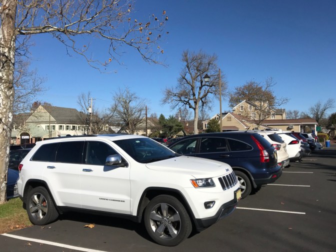 White Jeep Grand Cherokee at end spot in row in parking lot.
