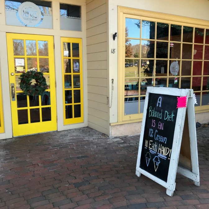 Sign in front of Nina's Ice Cream Shop that says A BALANCED DIET IS AN ICE CREAM IN EACH HAND!