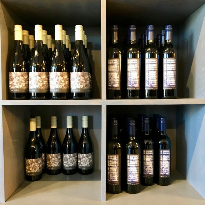 Wine bottles on shelves in four cubbyholes.