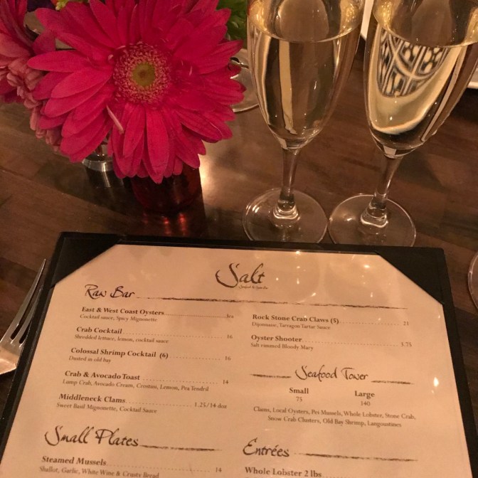 Two champagne glasses and menu at Salt restaurant.