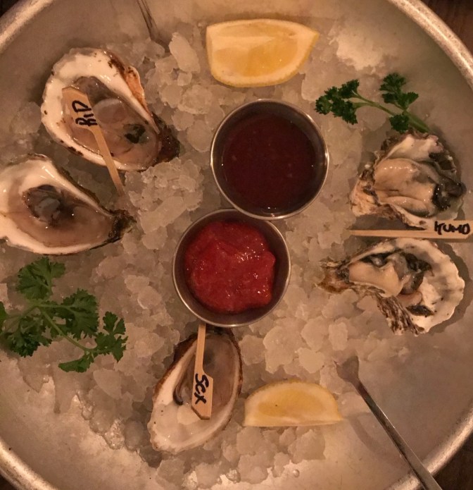 Steel bowl filled with ice and five oysters.