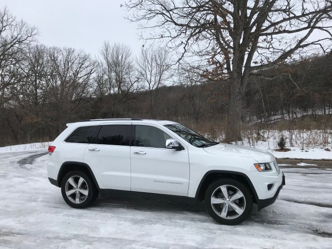 White Jeep Grand Cherokee parked on ice and snow-covered parking lot.