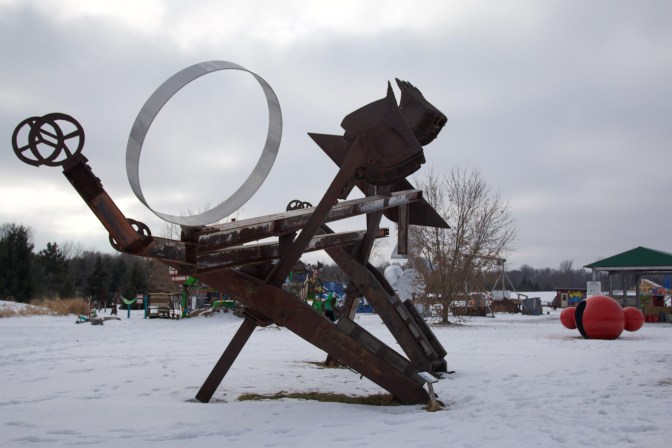 Metal sculpture with elements including backhoe shovels and metal girders.