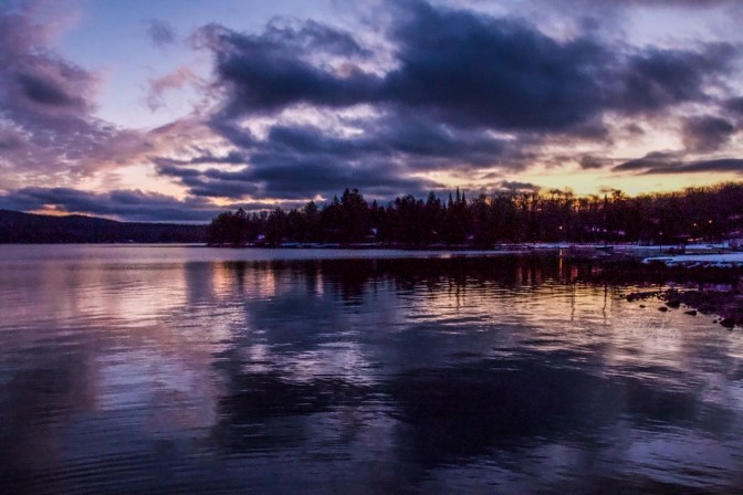 Twilight at tree-lined lake.