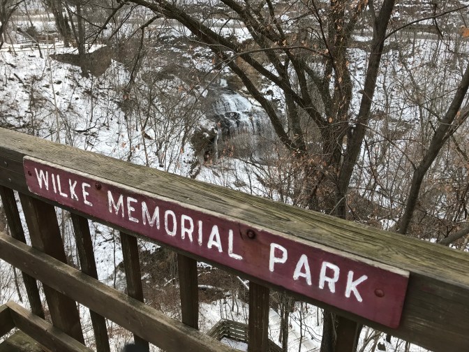 Sign on railing that says Wilkie Memorial Park overlooking a waterfall.