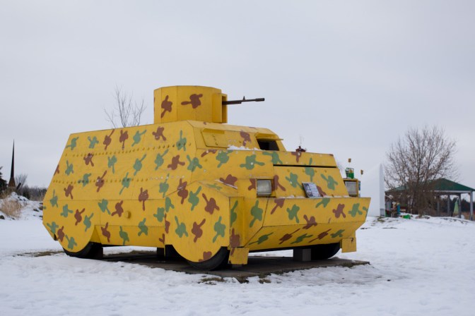 Sculpture of infantry fighting vehicle, covered in yellow with green camouflage.