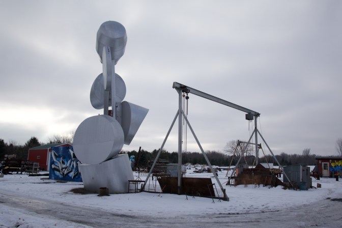 Two art installations - one is a series of interconnected half-circles, the other is a metal lift.