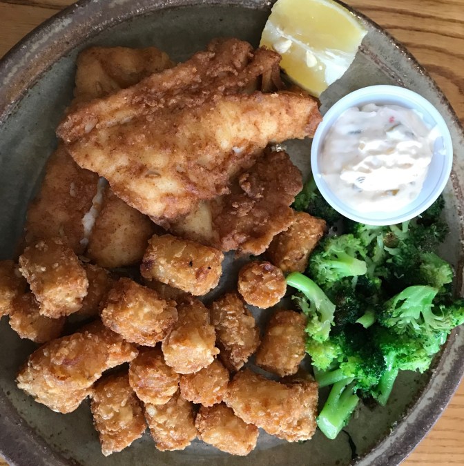 Plate with fried cod, tater tots, broccoli, and tartar sauce.