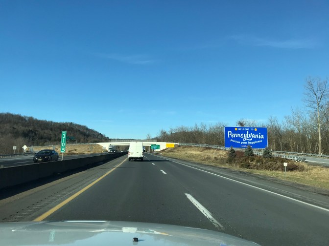 View of I-80 with blue welcome sign for Pennsylvania on right side of road.