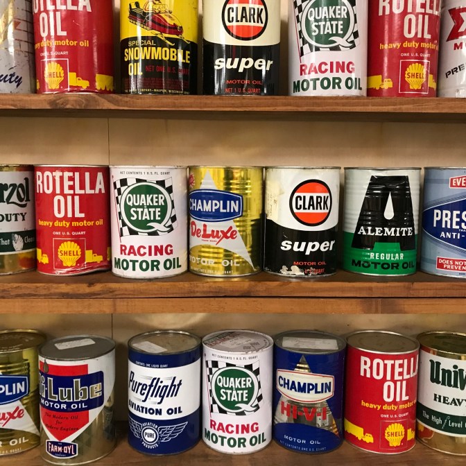 Three shelves of oil cans including Quaker State, Rotella, Clark, and Champlain.