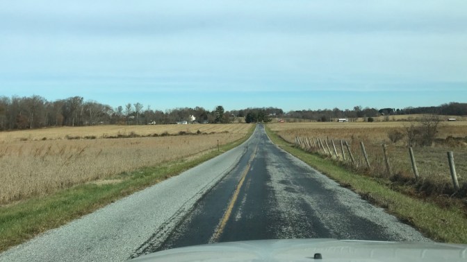 View of two-lane county road with farmland on either side.