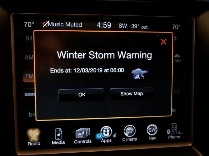 Car dashboard display with pop-up message WINTER STORM WARNING ENDS AT 13/03/2019 AT 6:00 PM.