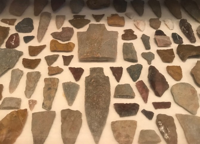 Stone arrowheads and tools in display case.