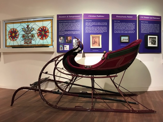 Wooden sleigh in front of wall display.