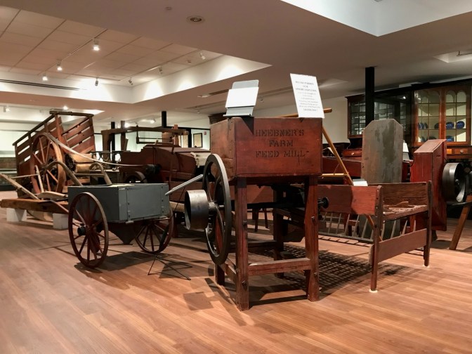 18th and 19th century agricultural equipment, in middle of museum floor.