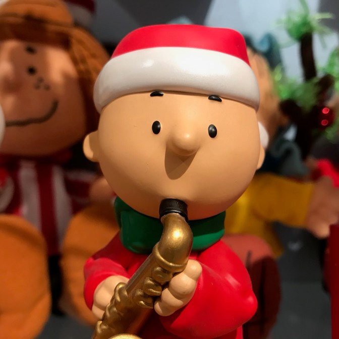 Charlie Brown figurine, dressed in a Santa outfit, playing a saxophone.