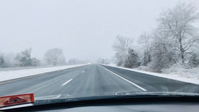 Snowy roadway during winter storm.