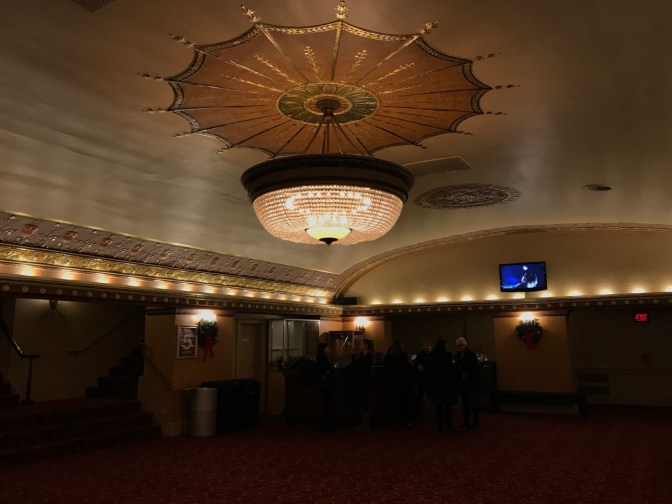 Small chandelier hanging from ceiling in lobby.