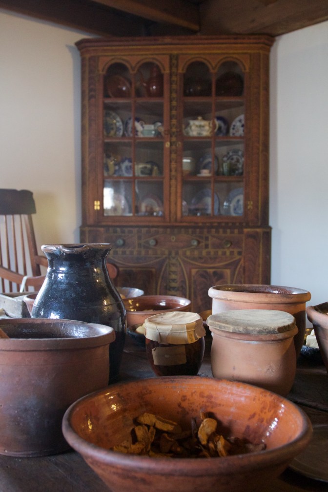 Table with cooking jars and bowls, with a corner cabinet in background.