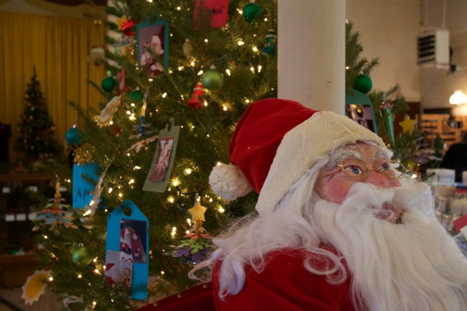 Santa Claus doll beside a Christmas tree.