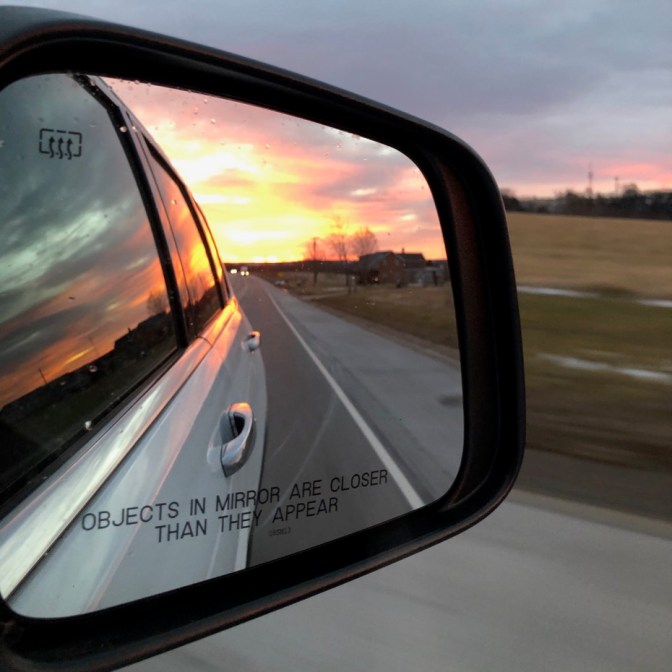 View of sunset in car mirror.