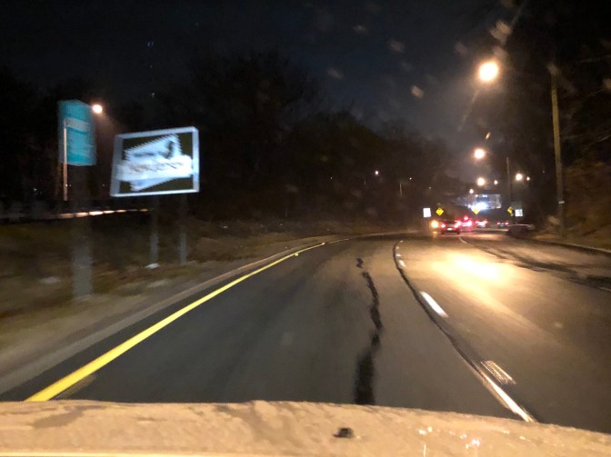 Highway in the rain, with sign along left side that says Welcome to New Jersey.