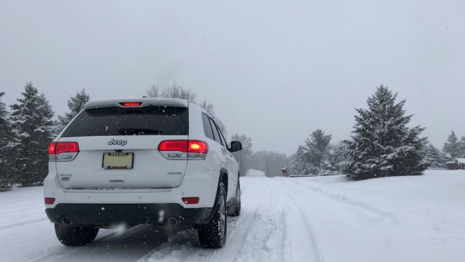 White Jeep Grand Cherokee, parked on snow-covered road.