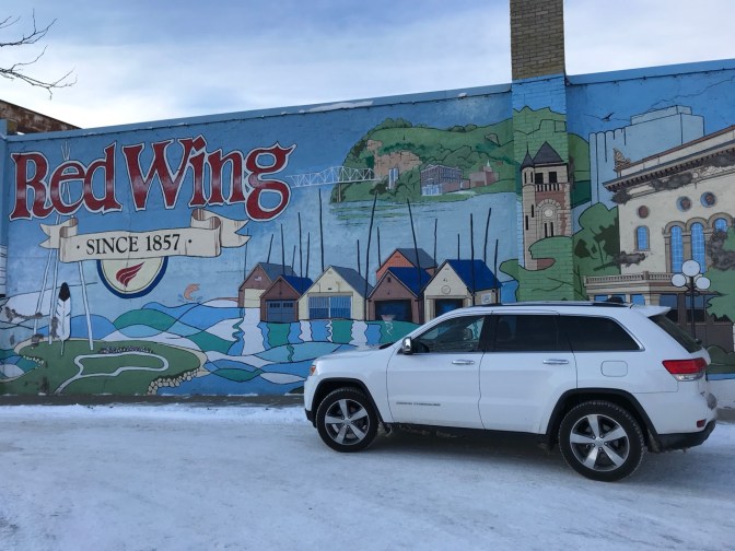 White Jeep Grand Cherokee in front of building mural of town, with a sign that says RED WING SINCE 1857