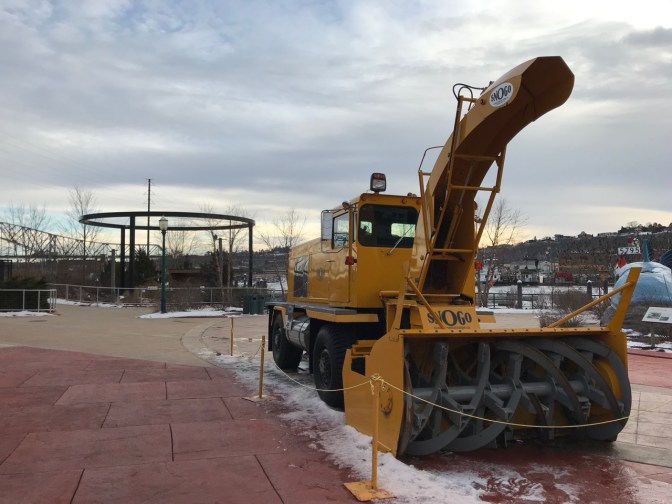 Snogo Snow Plow, in yellow, in plaza.