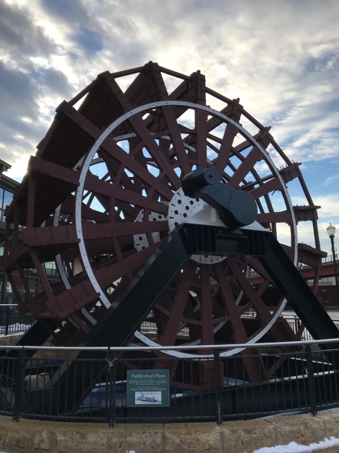 Paddlewheel on display in plaza.