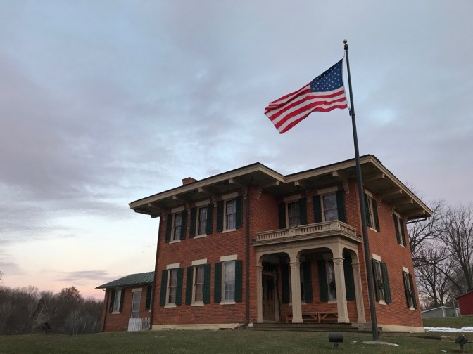House of President Ulysses S. Grant, a two-story brick home, with a large American flag flying from a flag pole in front of the house.