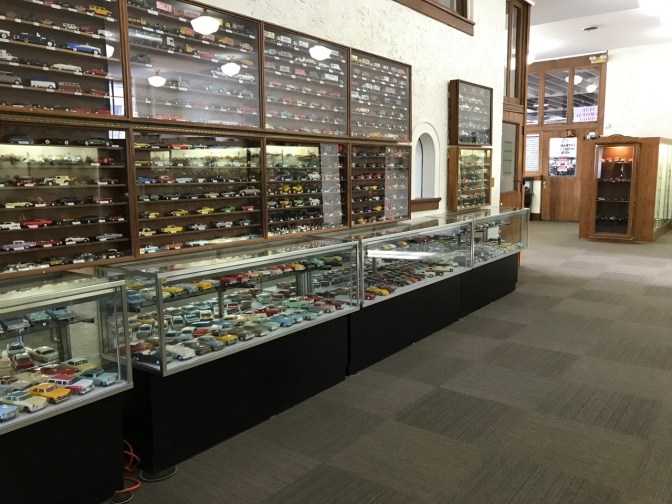 Interior of museum, with glass cases holding model and toy cars.