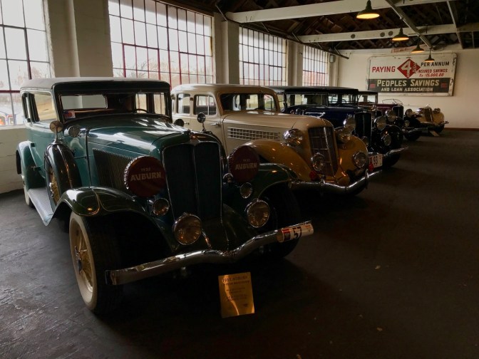 Line of five Auburn and Cord automobiles.