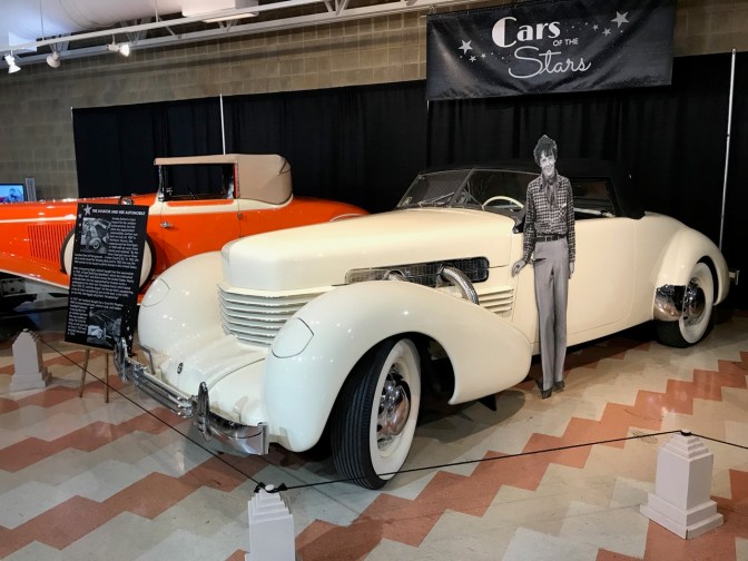 Cutout of Amelia Earhart, standing in front of a Cord car.